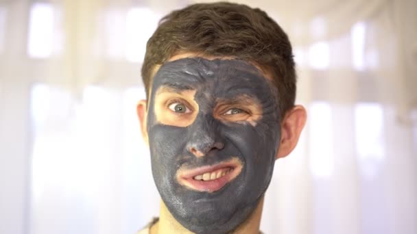 Porträt eines jungen Mannes mit einer Creme- oder Tonmaske im Gesicht. — Stockvideo