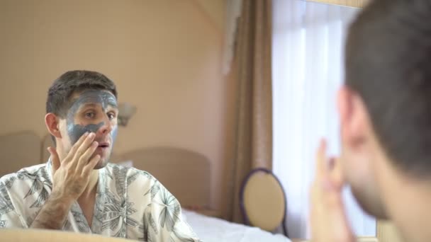 A young man uses a cream cosmetic mask for the face. Skin care. — Stock Video