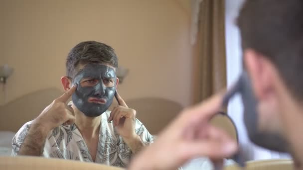 Nadenkende man gebruikt een cosmetische crème gezichtsmasker. Huidverzorging. — Stockvideo