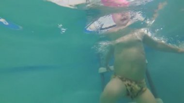 Küçük bir çocuk havuzu, ağır çekim yüzmeyi öğrenir.