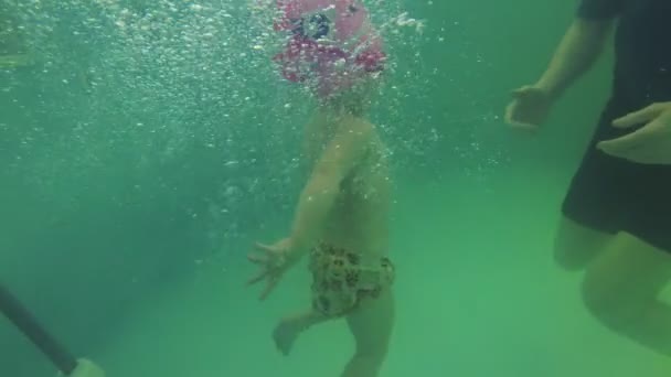 Uma criança pequena aprende a nadar na piscina . — Vídeo de Stock