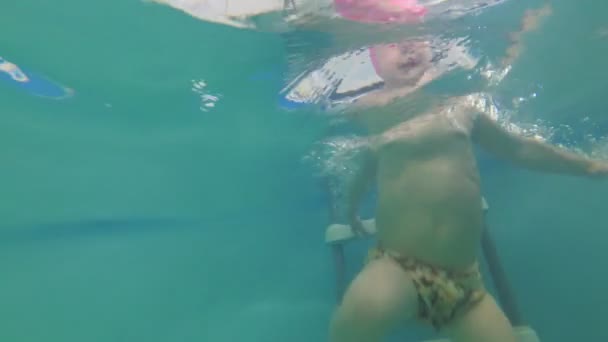Een klein kind leert om te zwemmen in het zwembad, slow-motion. — Stockvideo