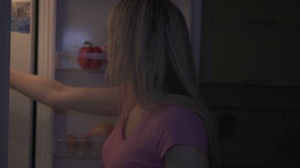 Nacht, Küche, Frau zieht ein Stück Kuchen aus dem Kühlschrank. — Stockvideo