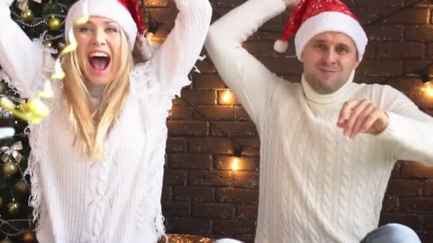 Vacaciones de año nuevo, una joven pareja divirtiéndose cerca del árbol de Navidad . — Vídeo de stock