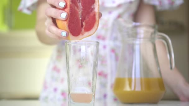 Femeia din bucătărie stoarce sucul din grapefruit, mișcare lentă . — Videoclip de stoc