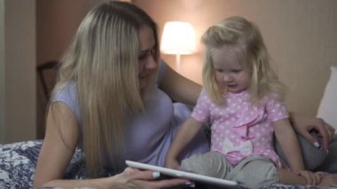 Bir kadın ve bir çocuk ile bir tablet üzerinde yatak odasında.