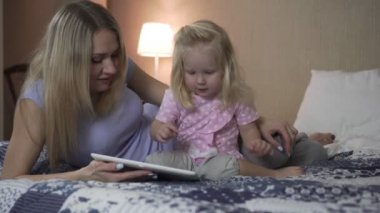Bir kadın ve bir çocuk ile yatakta bir tablet bilgisayar.