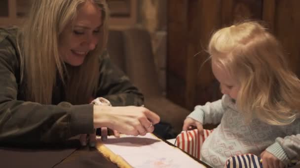 Mutter und Kind malen Bleistift am Tisch im Café. — Stockvideo