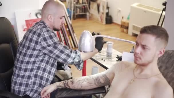 Tatuering mästaren gör en tatuering i salongen. — Stockvideo