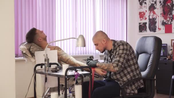 Ένας άνθρωπος κάνει ένα τατουάζ στο σαλόνι. Επαγγελματική τατουάζ καλλιτέχνης κάνει μια δερματοστιξία. — Αρχείο Βίντεο