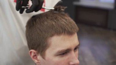 Genç bir adam bir kuaför dükkanı saçında keser.