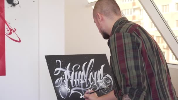 Un artiste contemporain peint un tableau dans un atelier d'art. Style calligraffiti . — Video