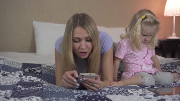 Γυναίκα και παιδί με gadgets στο κρεβάτι. — Αρχείο Βίντεο