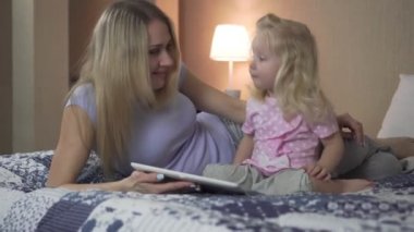 Mutlu aile, kadın ve çocuk yatağa evde tablet bilgisayar kullanarak.