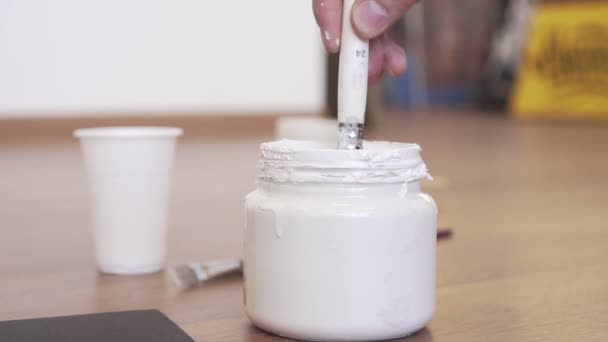 De kunstenaar dips de borstel in een pot verf. — Stockvideo