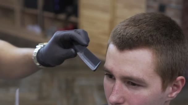 Barbier, un homme se coupe les cheveux dans un salon de coiffure, gros plan . — Video