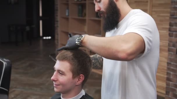 Un barbero con barba corta a un cliente en una peluquería . — Vídeos de Stock