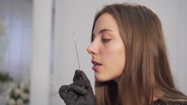 Woman tattooist licks a tattoo machine needle. Portrait of a woman tattooist. — Stock Video