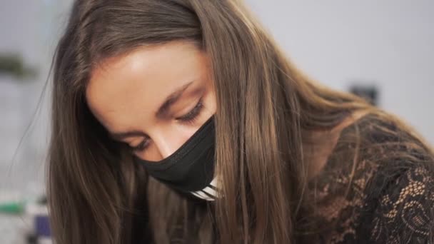 Jonge vrouwelijke tattoo kunstenaar in een beschermend masker. — Stockvideo