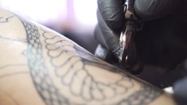 Dövme sanatçısı dövme otomatik dövme makinesi, yakın çekim çizer.