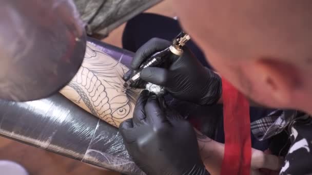 Молодий чоловік, художник татуювання, зробить татуювання в салоні . — стокове відео
