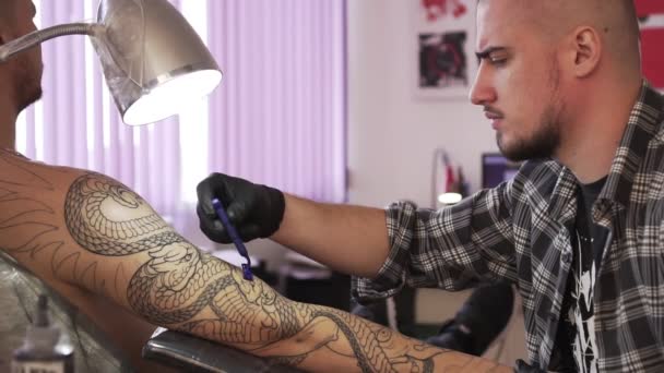 Male tattoo artist shaves the customers hand before the tattoo. — Stock Video