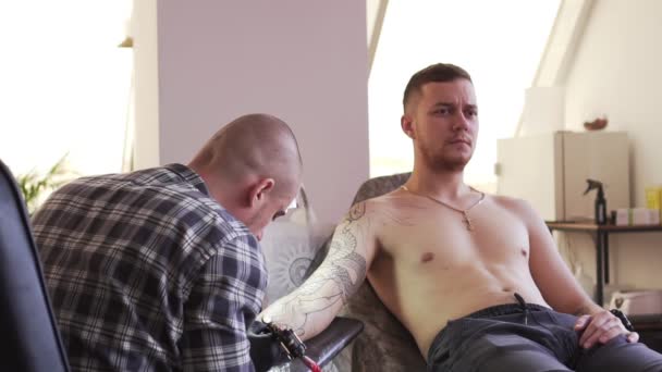 Processo tatuaggio. Un uomo soffre di dolore durante il tatuaggio . — Video Stock