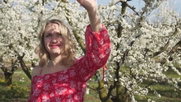 Retrato de una mujer joven sobre el fondo de árboles florecientes de primavera . — Vídeo de stock