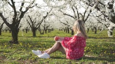 Bahar, çiçekli ağaçlar, meyve bahçesinde elma yiyen genç bir kadın..