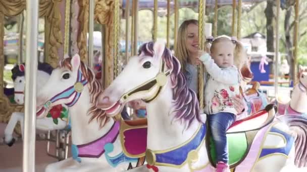 En kvinna och ett barn som rider på en häst på en karusell. — Stockvideo