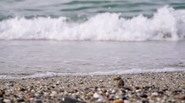Deniz dalgaları ve taşlı kumsal, yavaş çekim. Deniz sörfü, yakın çekim.