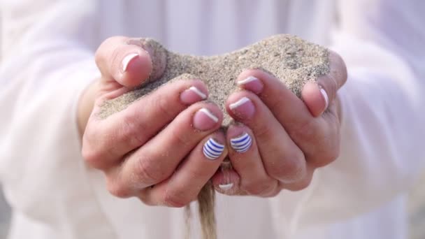 砂は女性の指を通して注ぐ、クローズアップ. — ストック動画
