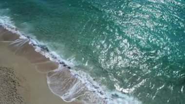 Güzel turkuaz deniz, dalgalar ve kumlu plaj, havadan görünümü. Yavaş çekim.