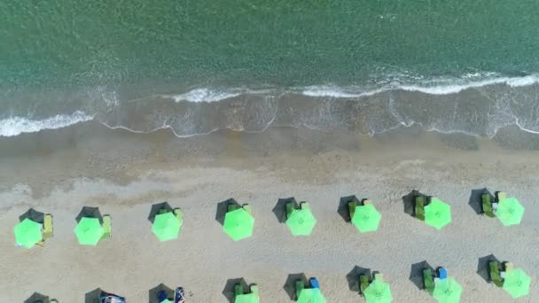 Sombrillas, el mar y la playa de arena. Vista aérea: los turistas toman el sol en la playa . — Vídeos de Stock