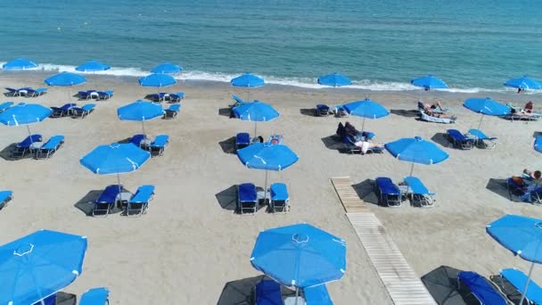 Turistler şemsiyelerin altında sahilde güneşlenmek. Sahil beldesi. — Stok video
