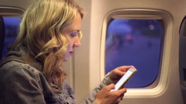 Young woman on a plane with a telephone. girl in the plane with a smartphone.
