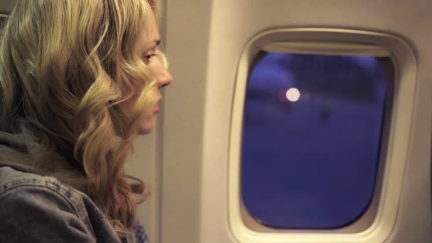 Fiatal nő keresi a repülőgépen ablak — Stock videók