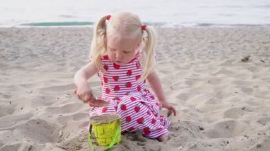 Kumlu plajda oynayan kız bebek.