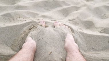 Erkek bacakları kuma uzanır, yakın çekim.