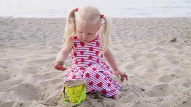Μωρό κορίτσι που παίζει στην αμμώδη παραλία. — Αρχείο Βίντεο