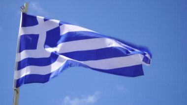 mavi gökyüzüne karşı rüzgarda bayrak direğinde Yunanistan bayrağı.
