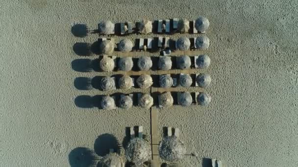 Zandstrand, zee en tropische parasols uit de zon, uitzicht op de lucht. — Stockvideo