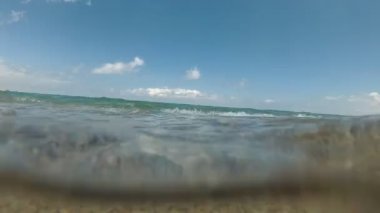 Yavaş çekim: deniz, dalgalar ve kumlu plaj, kamera ile sualtı eylem.