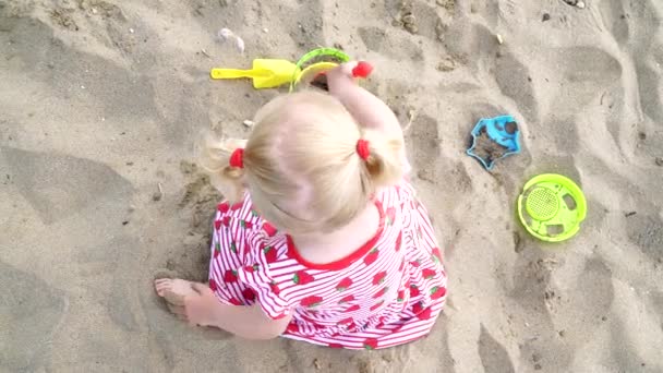 Baby girl playing in the sand with a spatula and a bucket. — Stock Video