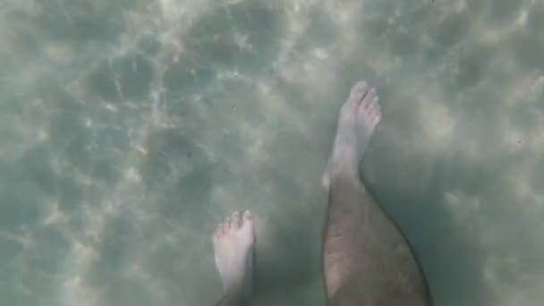 Een man loopt op de zee zandbodem, benen close-up. — Stockvideo