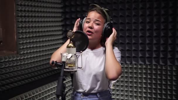 A young woman sings into a microphone in a recording Studio. — Stock Video