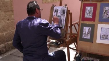 Yunanistan, Girit, Rethymno - Mayıs 2019. Bir erkek sanatçı Avrupa caddesinde resim yapıyor..