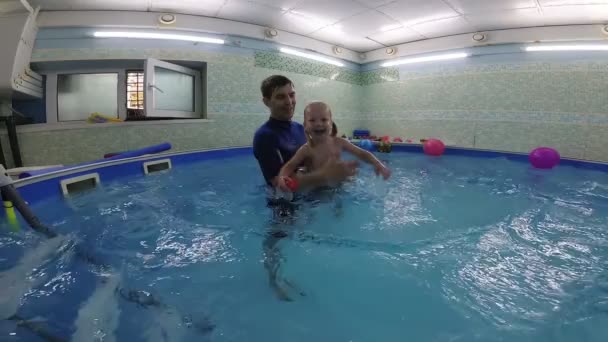 Un petit enfant apprend à nager dans la piscine avec un entraîneur . — Video
