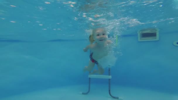 Child trains in the swimming pool. Baby girl swims in the pool. — Stock Video