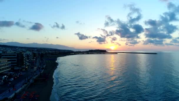 Prachtige zonsondergang op de zee tegen de achtergrond van de stad. — Stockvideo